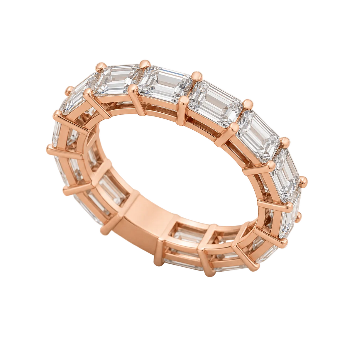 A rose gold eternity ring featuring a continuous row of baguette-cut clear gemstones, photographed on a textured light beige surface.