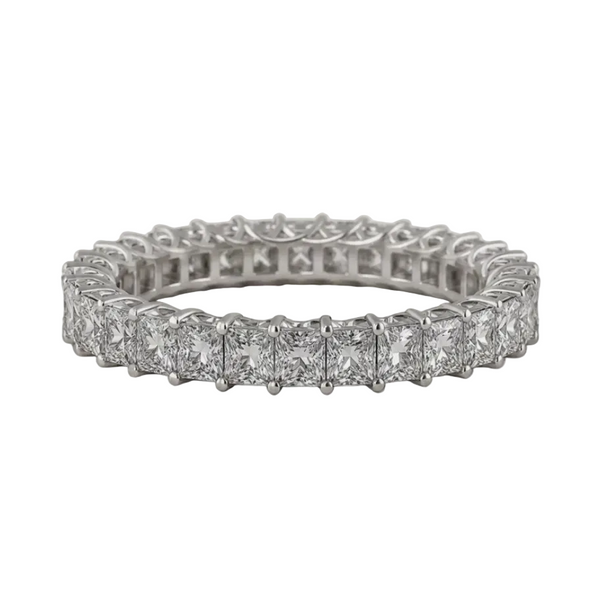 A silver-toned eternity ring featuring a row of princess-cut diamonds in a prong setting, displayed on a textured light beige background.
