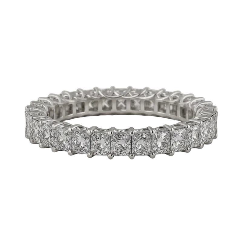 A silver-toned eternity ring featuring a row of princess-cut diamonds in a prong setting, displayed on a textured light beige background.