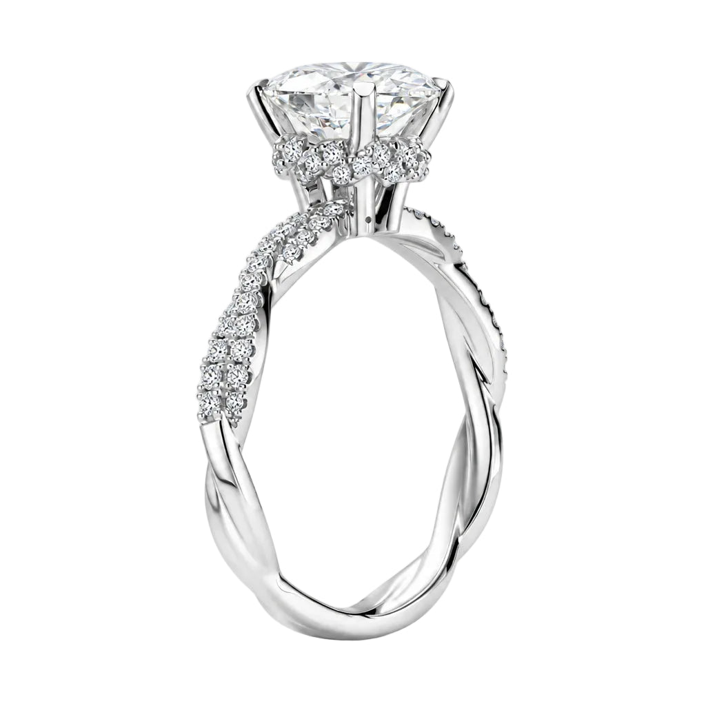 A silver-toned engagement ring with a large clear gemstone, surrounded by small accent stones, shown on a light gray background with callout lines and text describing features such as twisted pavé shank, hidden halo setting, high setting, and open-work gallery.