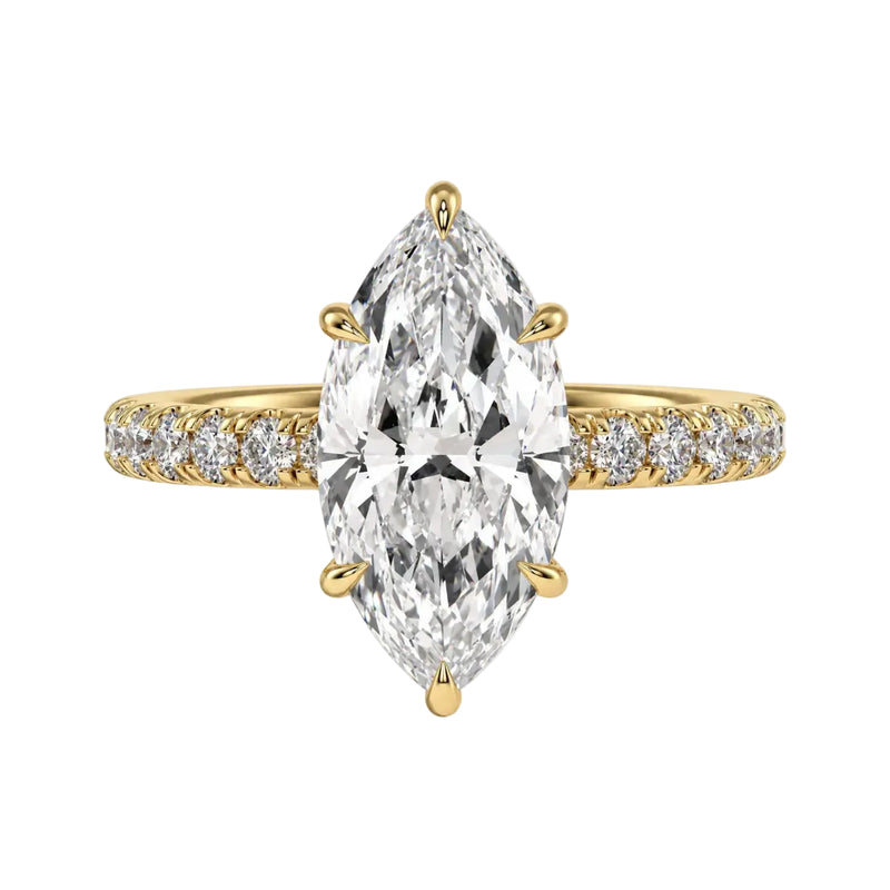 Gold ring with a large pear-shaped diamond and smaller diamonds on a beige background