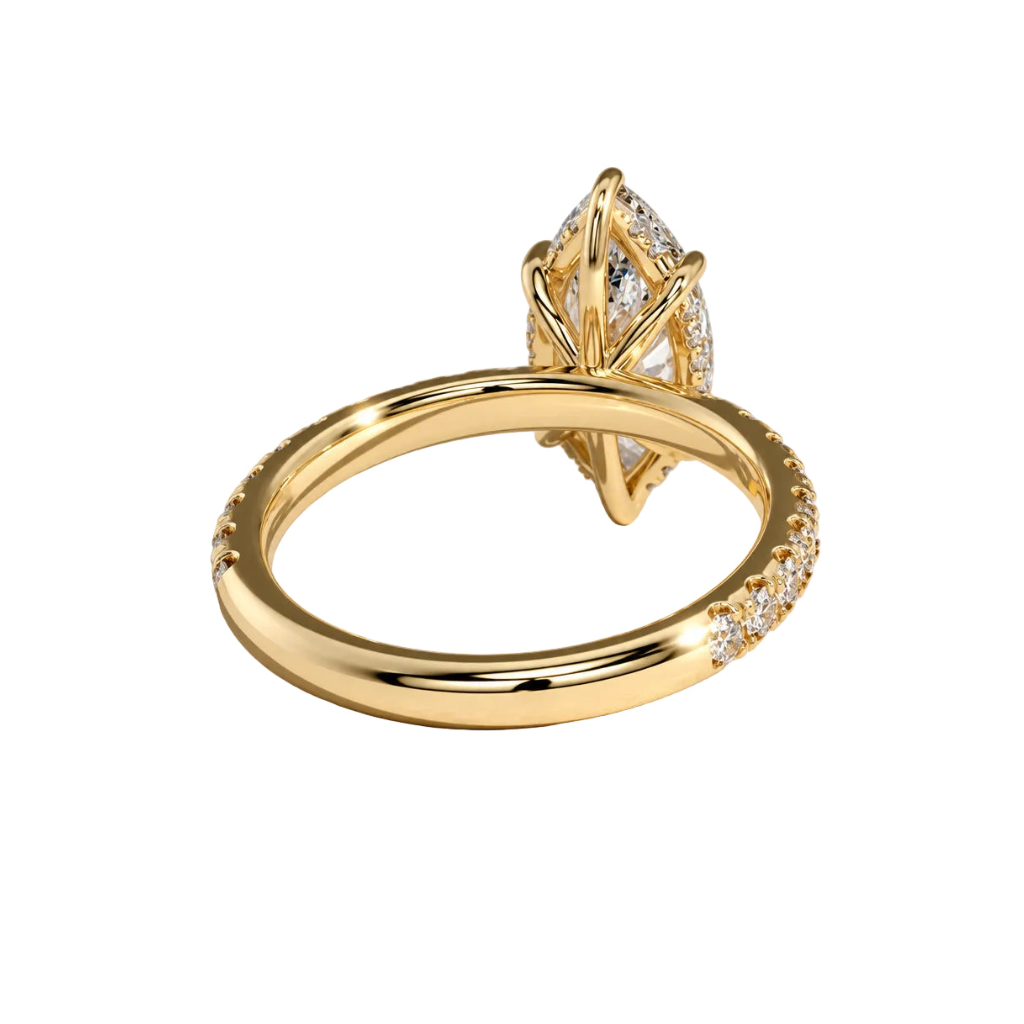 A yellow gold ring with a marquise-cut diamond center stone and a halo of smaller diamonds, shown on a clean light beige background.