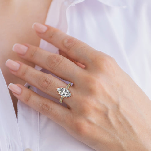 Close-up of a hand wearing a diamond ring with a blurred white background