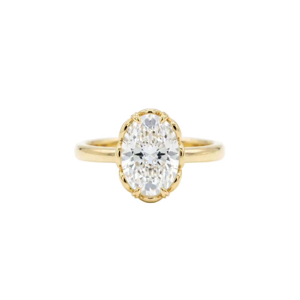 A yellow gold ring featuring an oval-cut clear gemstone in a scalloped bezel setting, shown against a plain white background.